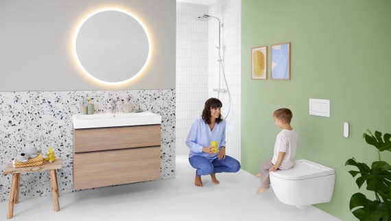 Kvinne og barn på et fargerikt bad med Geberit Option-speil og Geberit AquaClean Alba